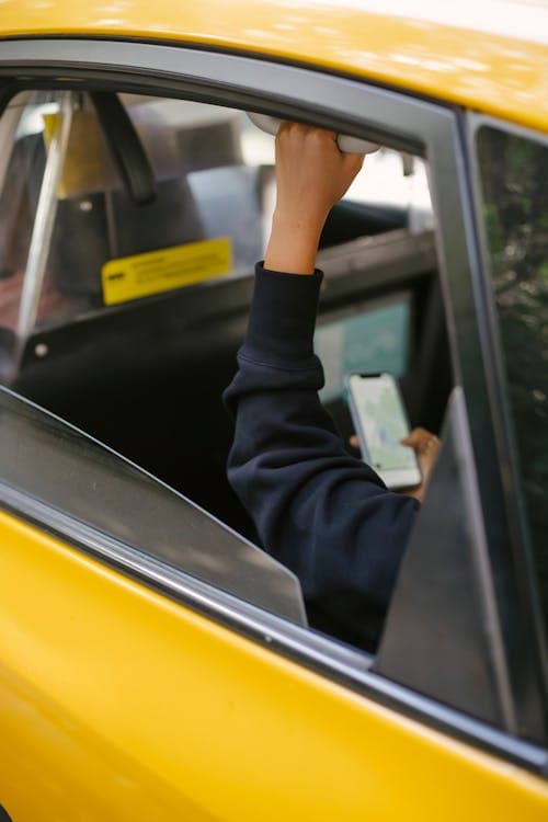 Passenger in the backseat of a rideshare vehicle using a smartphone, representing Uber and Lyft accident scenarios