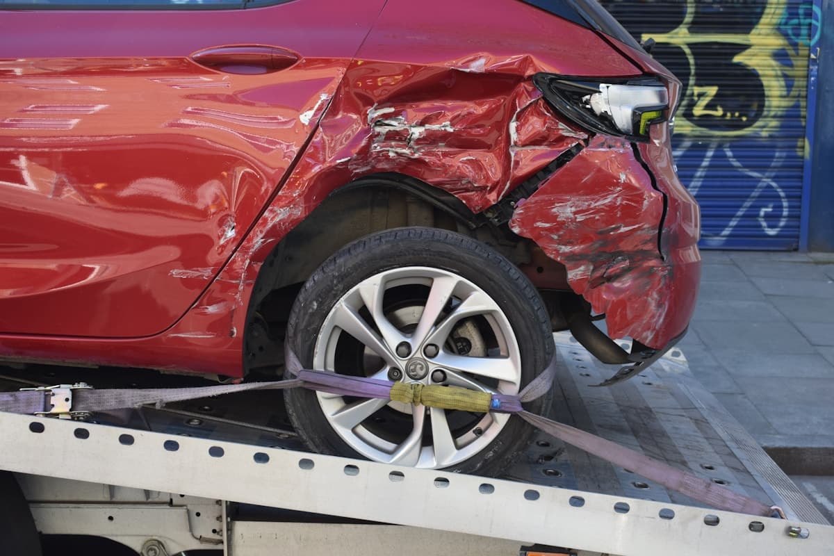 Heavily damaged red car on a flatbed tow truck after a total loss accident